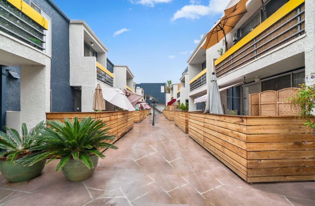 a courtyard with a wooden fence and planters on either side of it