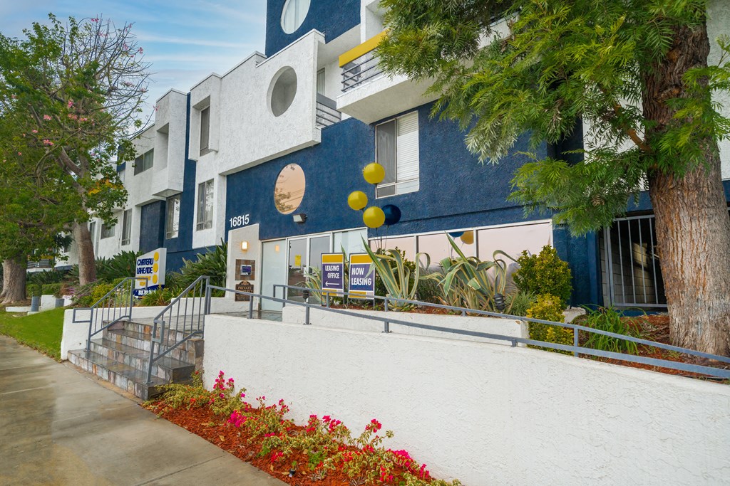a blue and white building with trees and flowers in front of it