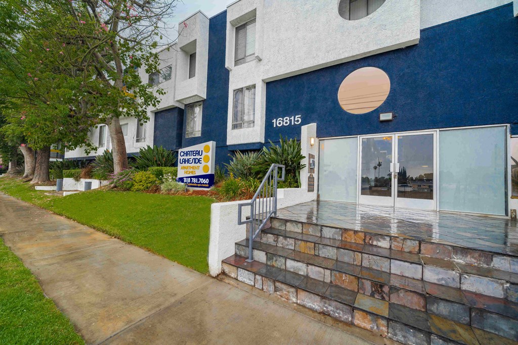 a blue and white apartment building with a sidewalk and stairs in front of it