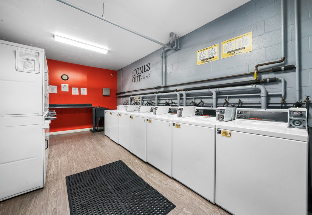 a laundry room with white machines and a red wall