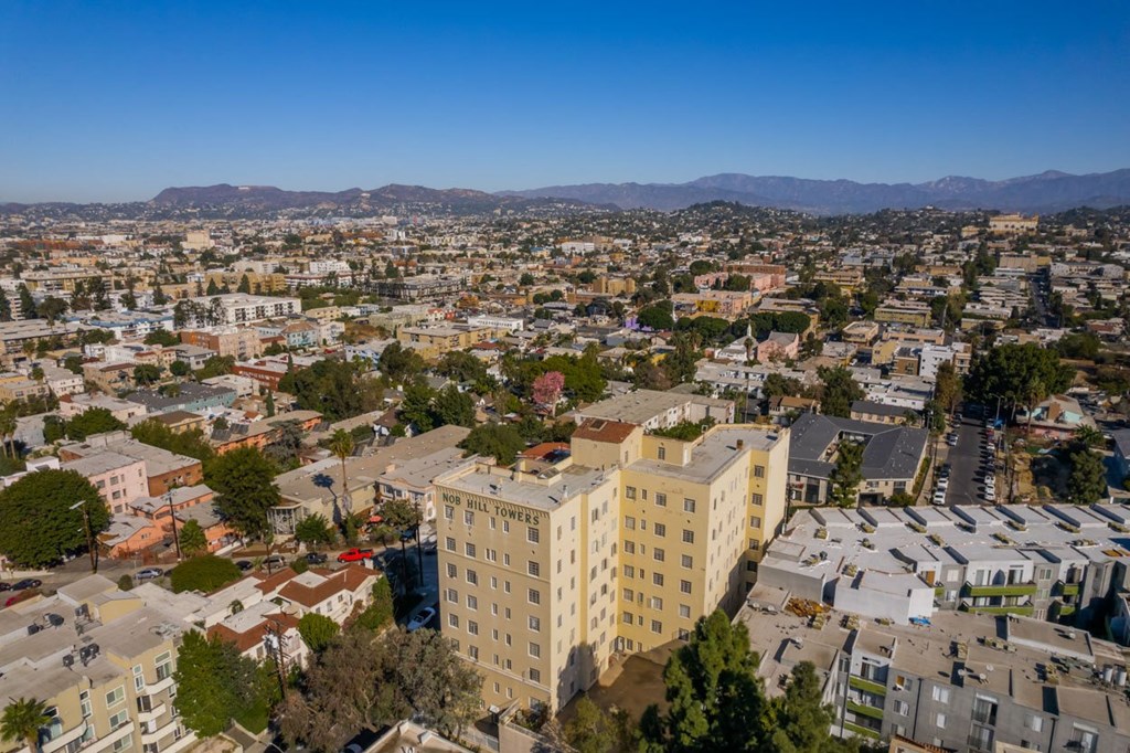 A cityscape with a large building in the center and a mountain range in the distance.