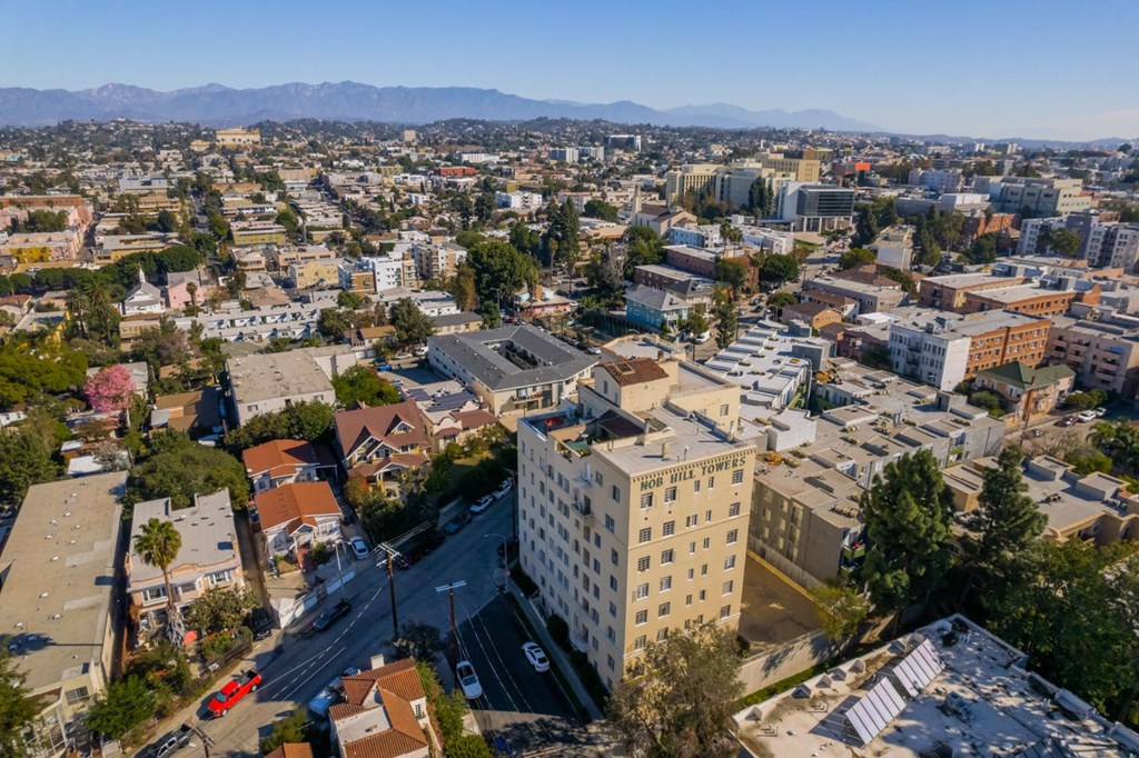 A cityscape with a large white building in the center and a mountain range in the background.