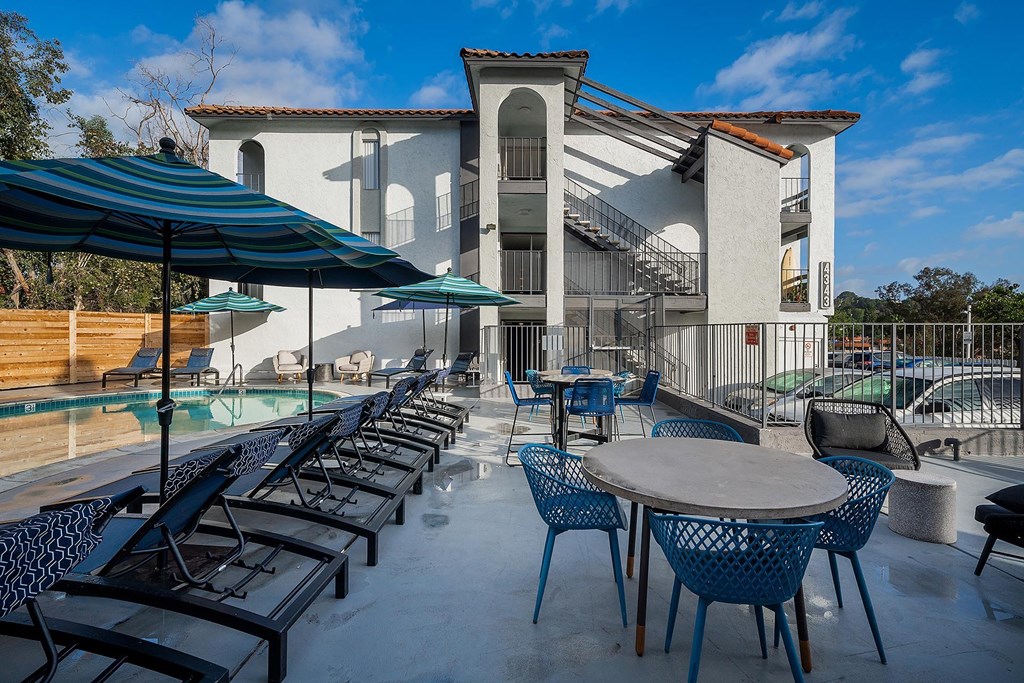 A patio with tables and chairs and a building in the background.