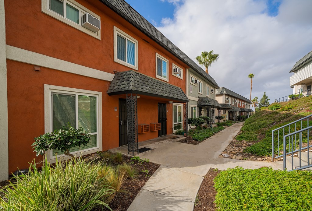 a row of orange houses with a sidewalk in front of them