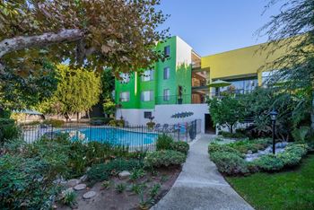 A green and yellow building with a pool in the backyard.
