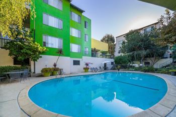 A swimming pool in front of a green and white building.