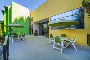 A patio with a table and chairs and a green umbrella.