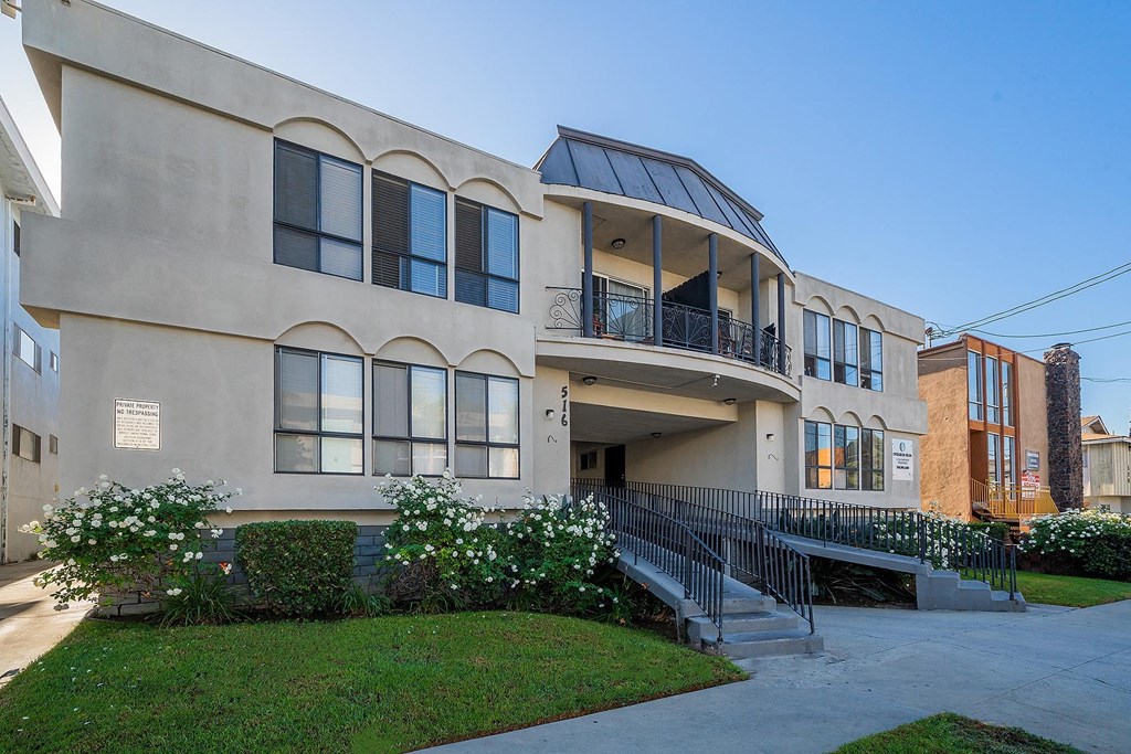 A building with a balcony and a staircase leading to the entrance.