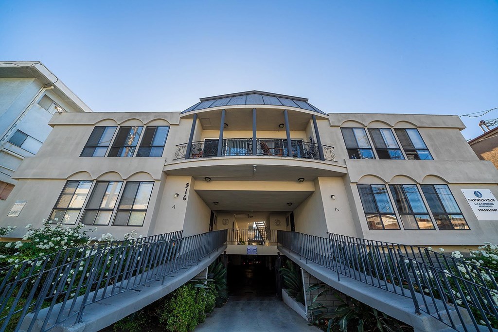 A building with a balcony and a sign that says "For Sale".