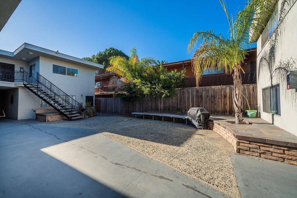 A concrete patio area with a black tarp and a wooden fence.