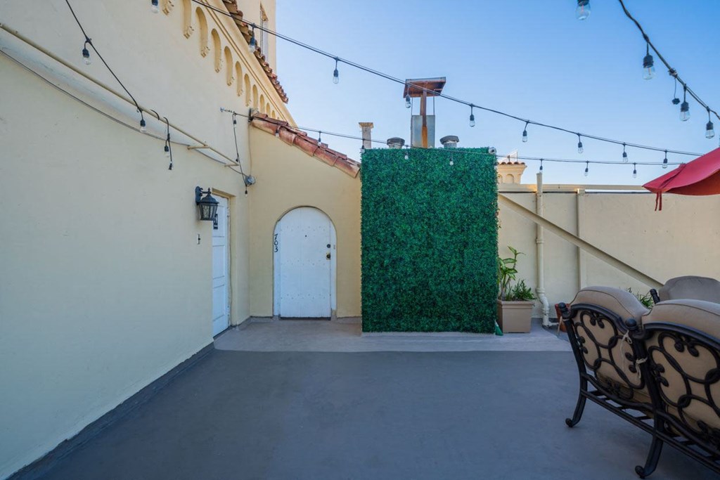 A patio with a wall of green plants and a white door.