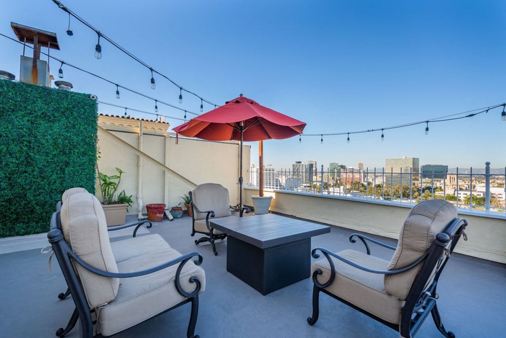 A patio with a table, chairs, and a red umbrella.