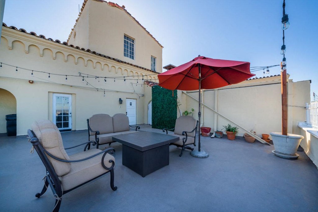 A patio with a table, two chairs and an umbrella.