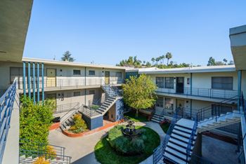 A courtyard surrounded by buildings with a tree in the middle.
