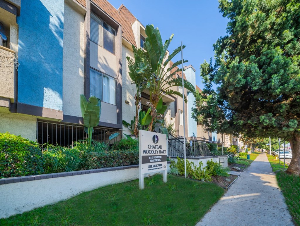 an apartment building with a sign in the grass in front