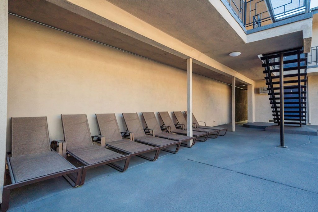 a row of lounge chairs in front of a wall with a spiral staircase in the background