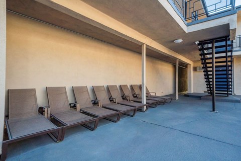 a row of lounge chairs in front of a wall with a spiral staircase in the background