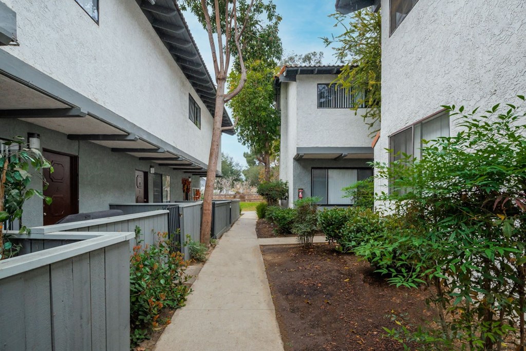 A long concrete pathway leads between two buildings.