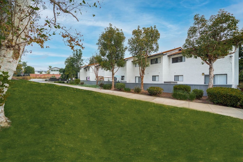A row of white houses with green lawns in front.