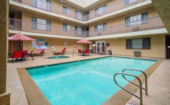 A large indoor pool with a diving board and lounge chairs.