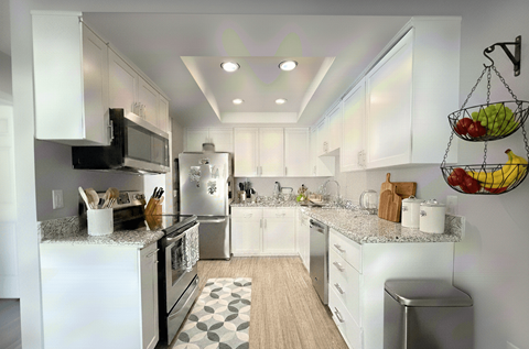 A modern kitchen with white cabinets and a black microwave.