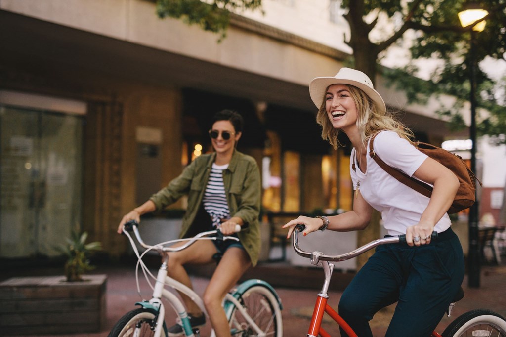 two women riding bicycles down the street on bikes