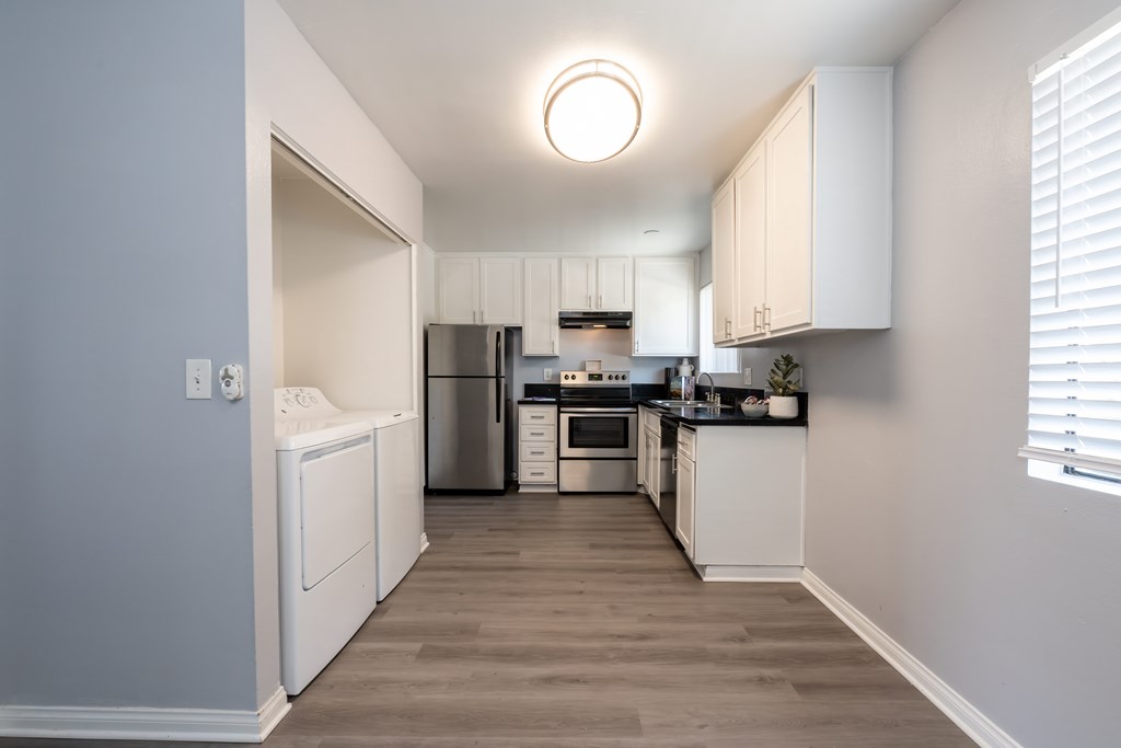 A kitchen with white cabinets and a wooden floor.