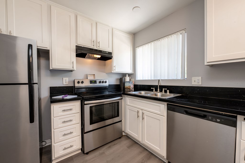 A modern kitchen with white cabinets and black countertops.