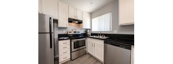 A modern kitchen with white cabinets and black countertops.