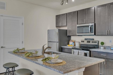A kitchen with a granite countertop and stainless steel appliances.