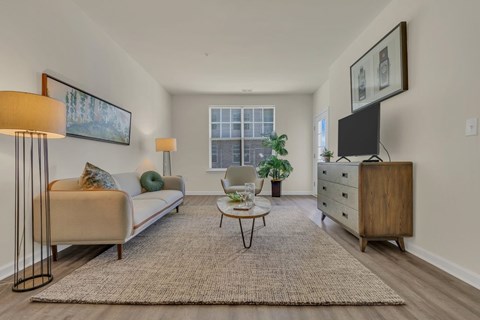 A living room with a beige couch, a coffee table, and a painting on the wall.