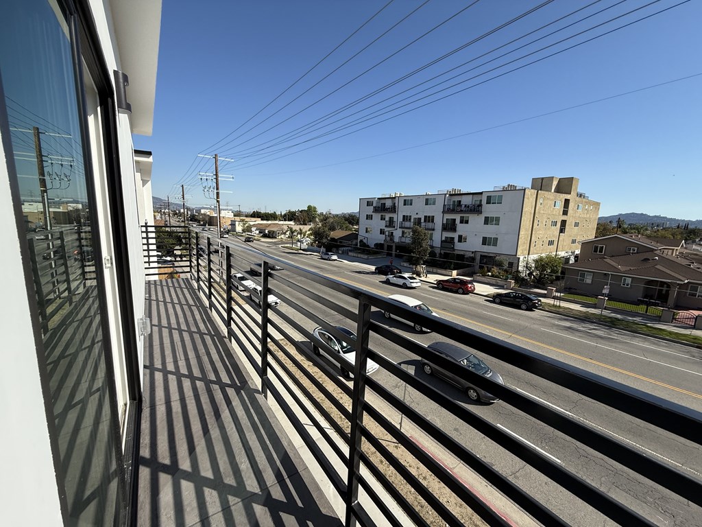 A view from a balcony looking out at a street with cars and buildings.