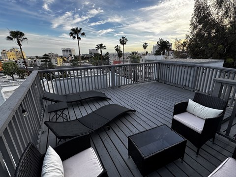 A balcony with black furniture and a view of the city.