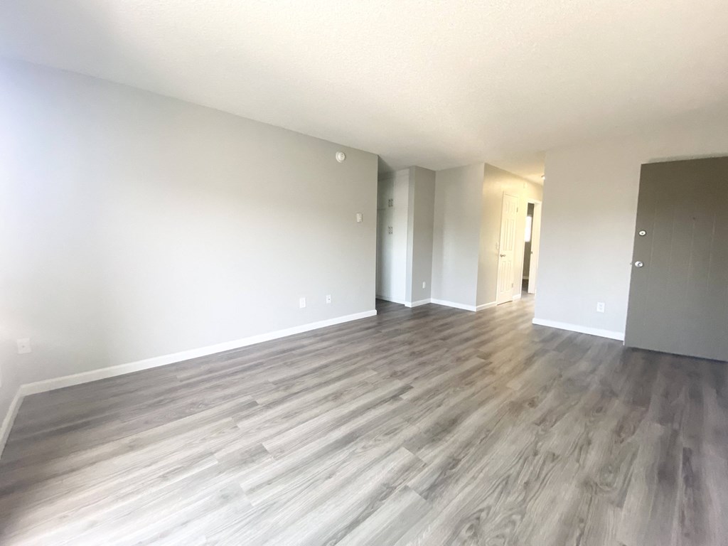 an empty living room with wood floors and white walls