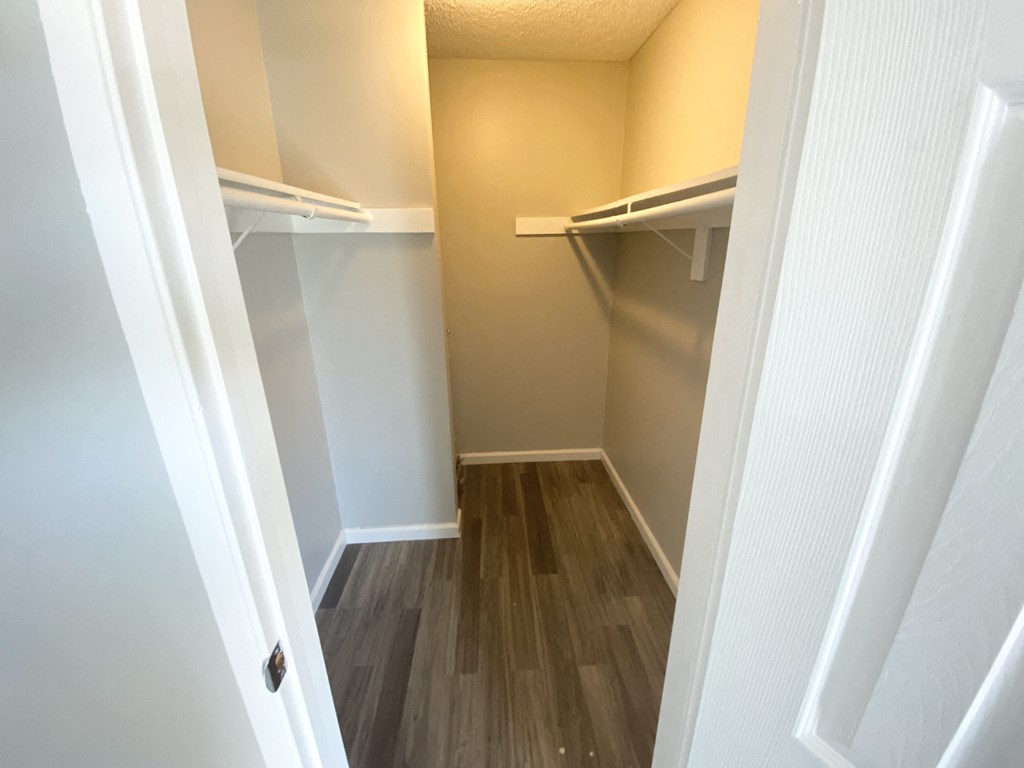 a spacious walk in closet in a renovated room with wood flooring
