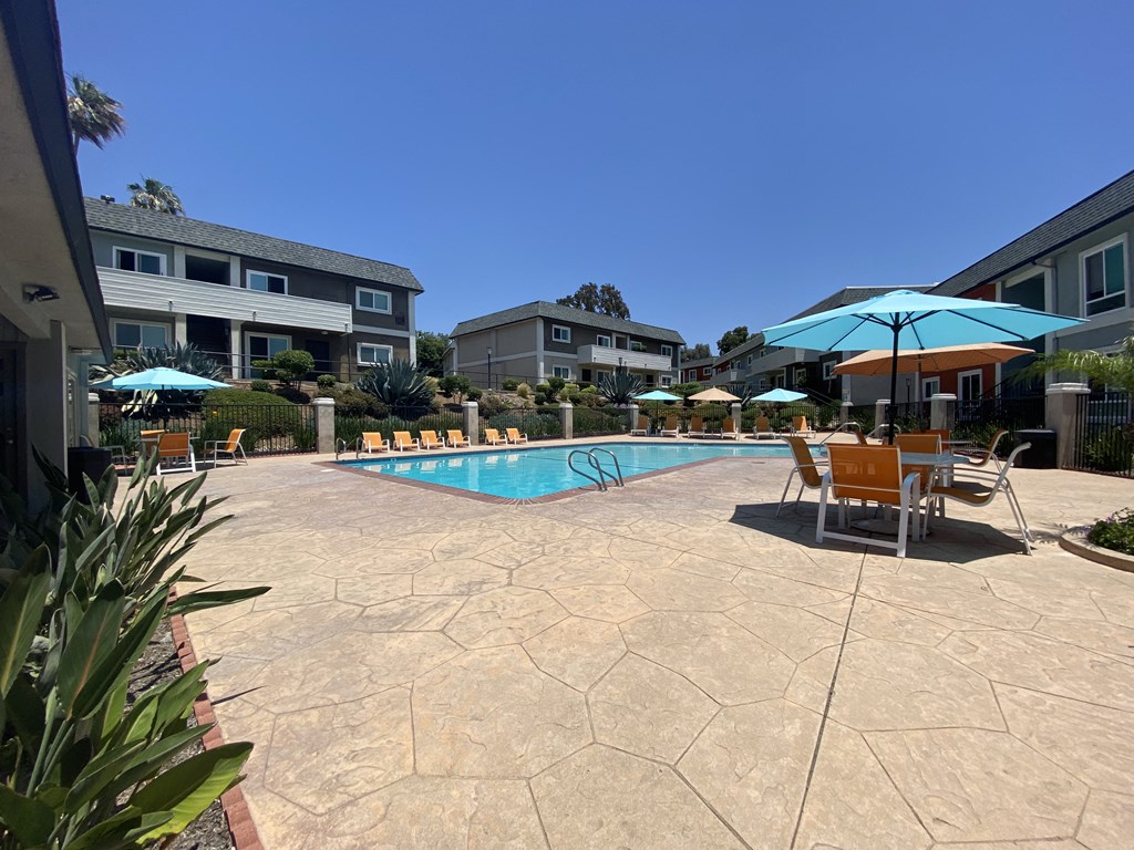 a swimming pool with chairs and umbrellas in front of a building