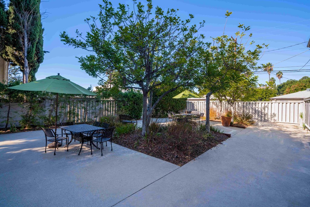 a patio with a table and chairs and a tree