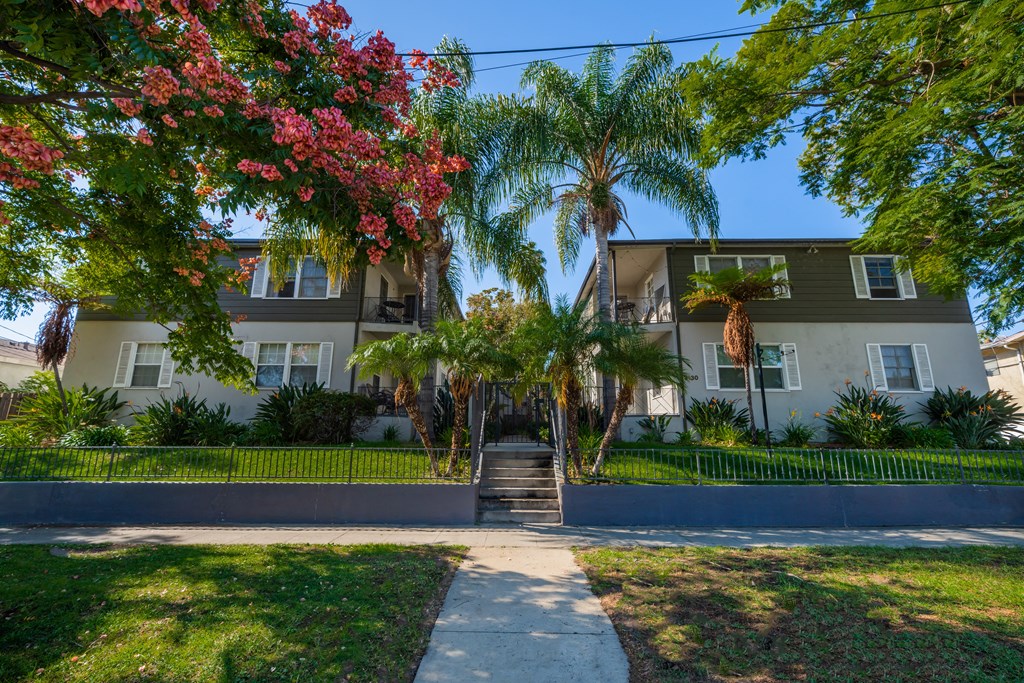 a home with a sidewalk and palm trees in front of it
