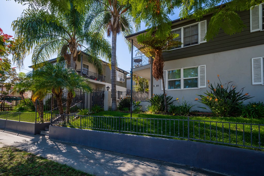 a street view of two apartment buildings with palm trees in front of them