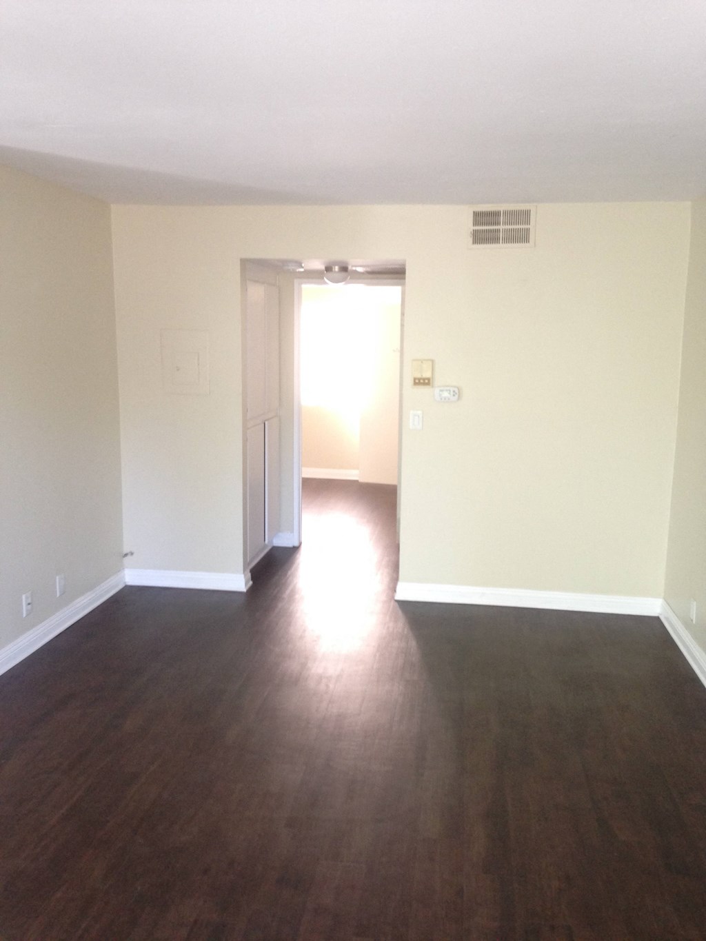 A room with a wooden floor and a doorway leading to another room.