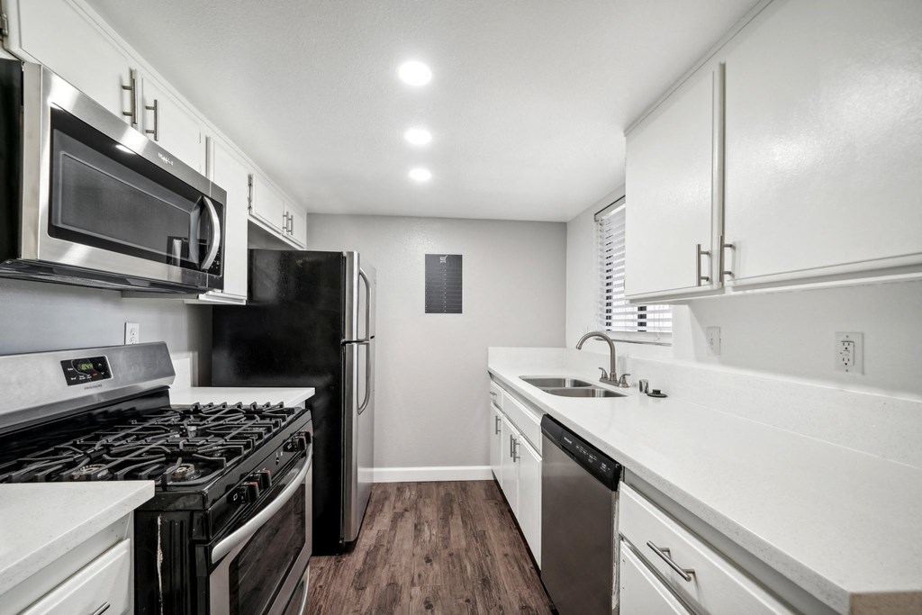 an empty kitchen with white cabinets and stainless steel appliances
