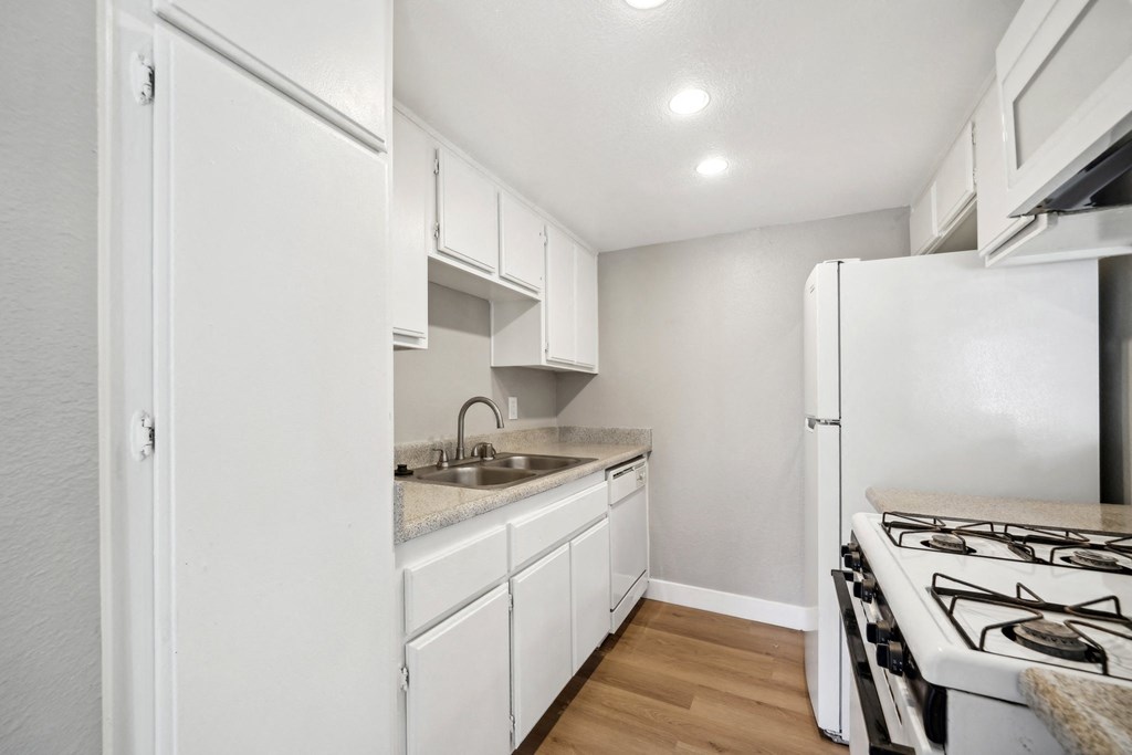 an empty kitchen with white cabinets and a stove and refrigerator