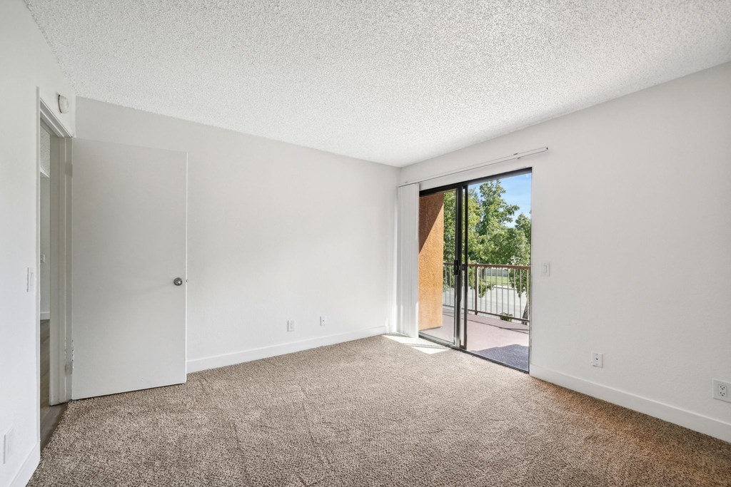 an empty living room with a sliding glass door to a patio