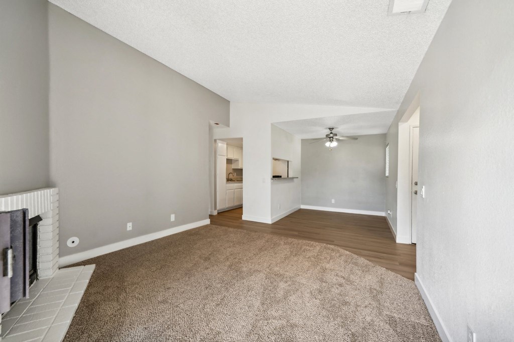 the spacious living room and dining room with white walls and carpeting