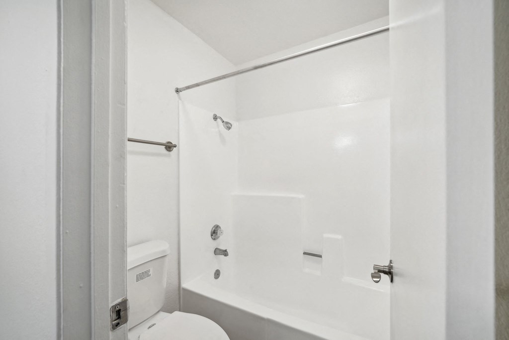 a white bathroom with a shower and a toilet