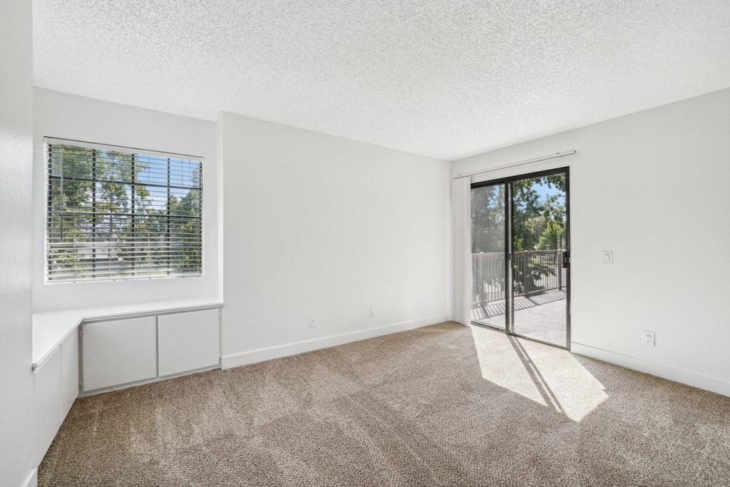 an empty living room with a sliding glass door to a patio