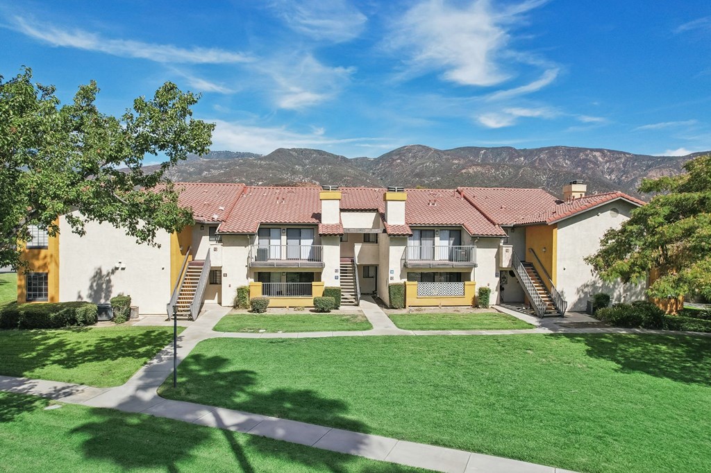 a large house with a lawn and mountains in the background