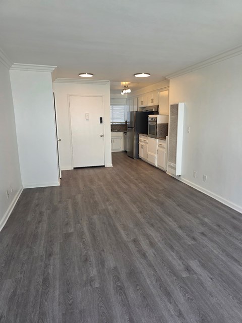 A kitchen with white cabinets and a black fridge is visible through a doorway.