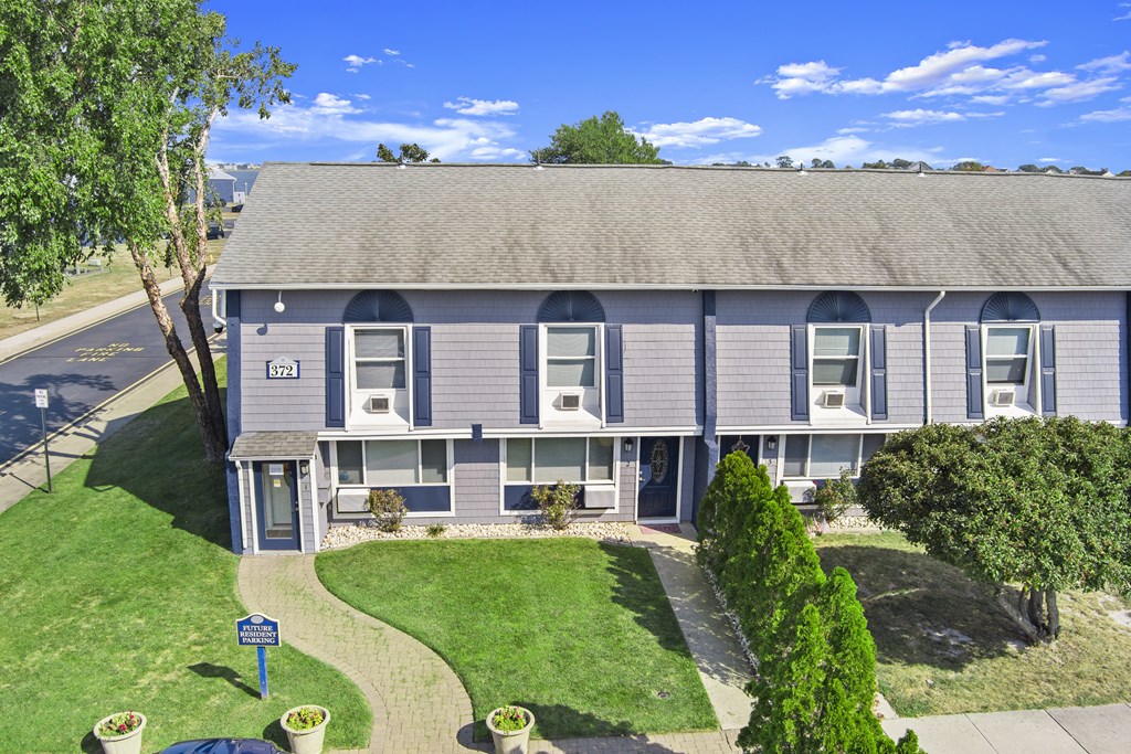 the front of a gray house with a yard and a road