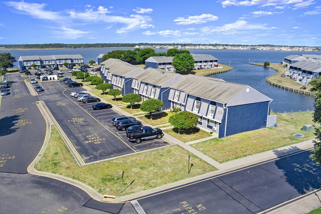 an aerial view of a building with a parking lot and a body of water